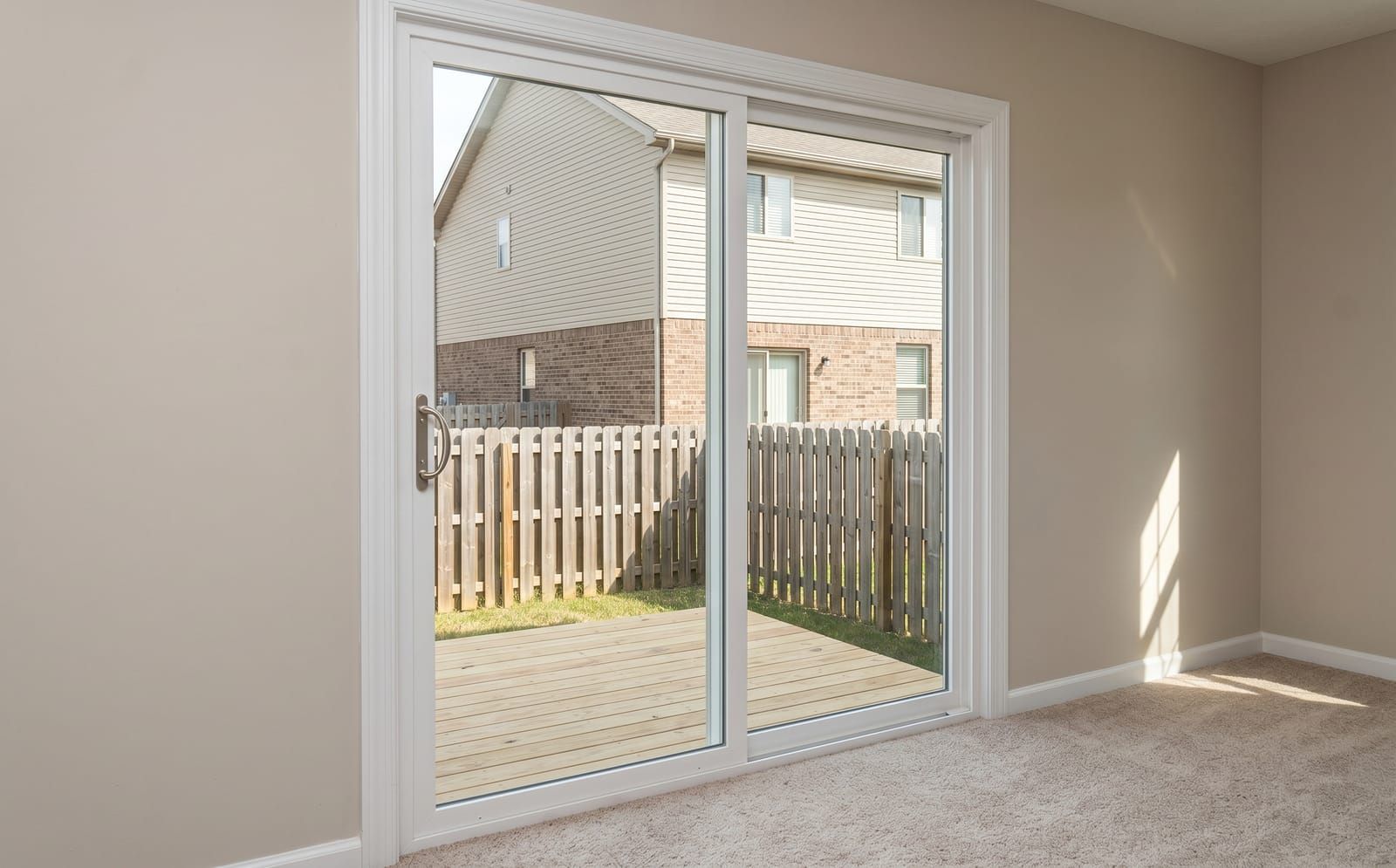 White-vinyl three-panel sliding patio door on the back of a St. Charles two-story home opening to a wood deck